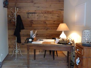 Una habitación con paneles de madera, un escritorio, una lámpara, un teléfono y un perchero.