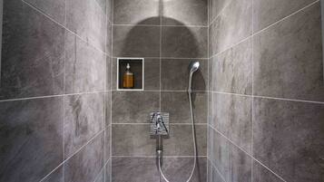 Un espace douche moderne doté d’un pommeau de douche à main et d’un panneau de commande fixé au mur.