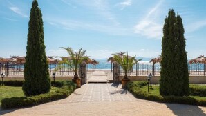 Un camino empedrado que lleva a una playa con palmeras y cielo despejado.