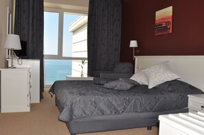 Une chambre à coucher comprenant un lit, un bureau, une chaise, une table de chevet, une lampe et un tableau accroché au mur.