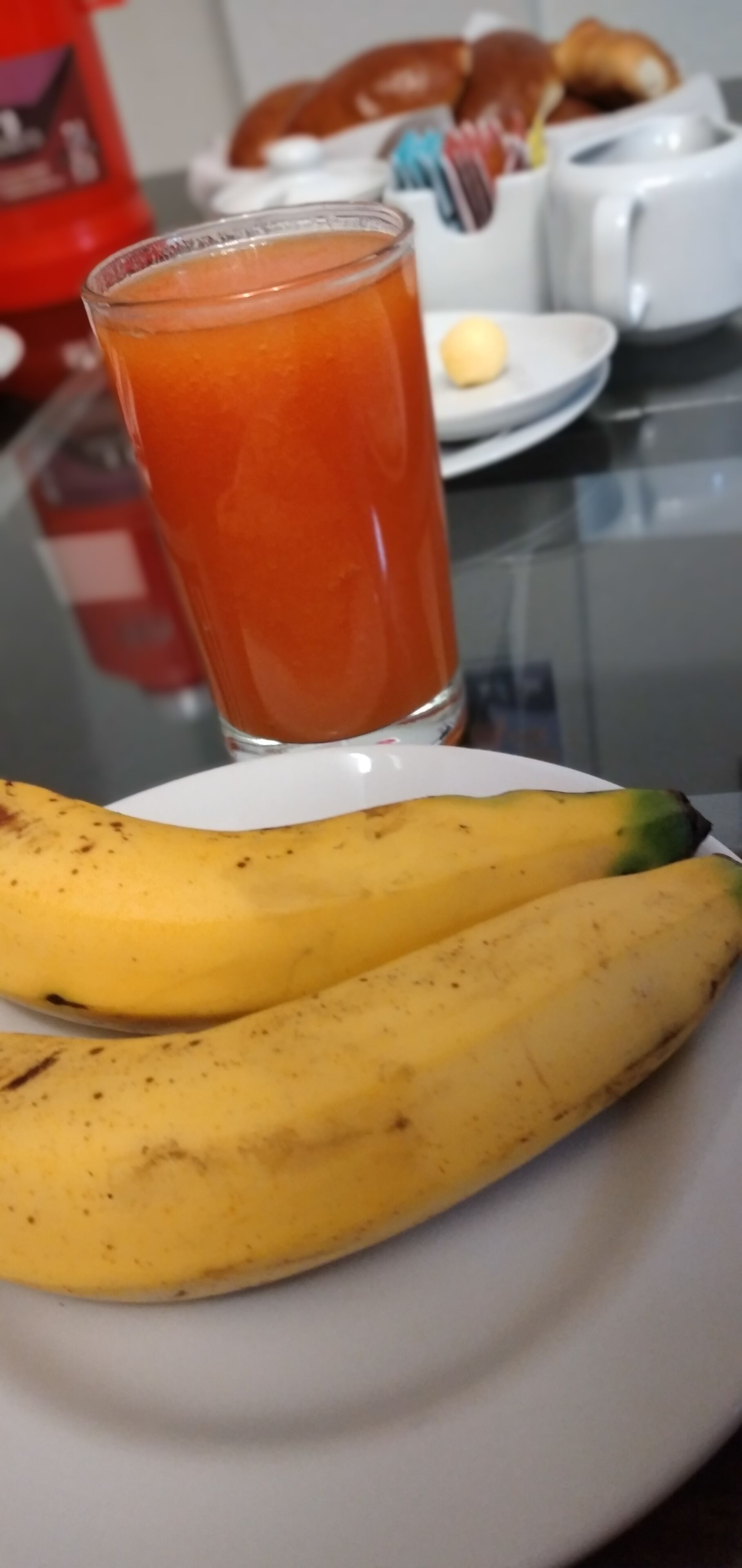 Um prato com duas bananas e um copo de suco de laranja sobre uma mesa.