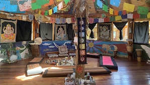 Une pièce dotée d’un plancher en bois, décorée de guirlandes et d’ornements en papier de différentes couleurs, et où sont exposés divers objets religieux.
