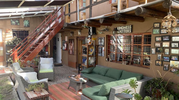 Un espace intérieur vaste et lumineux, avec un canapé vert, des meubles en osier et un escalier.
