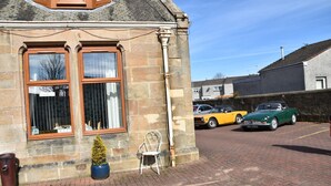 A stone building with two large windows and a small potted plant. - The Gables (Bathgate)
