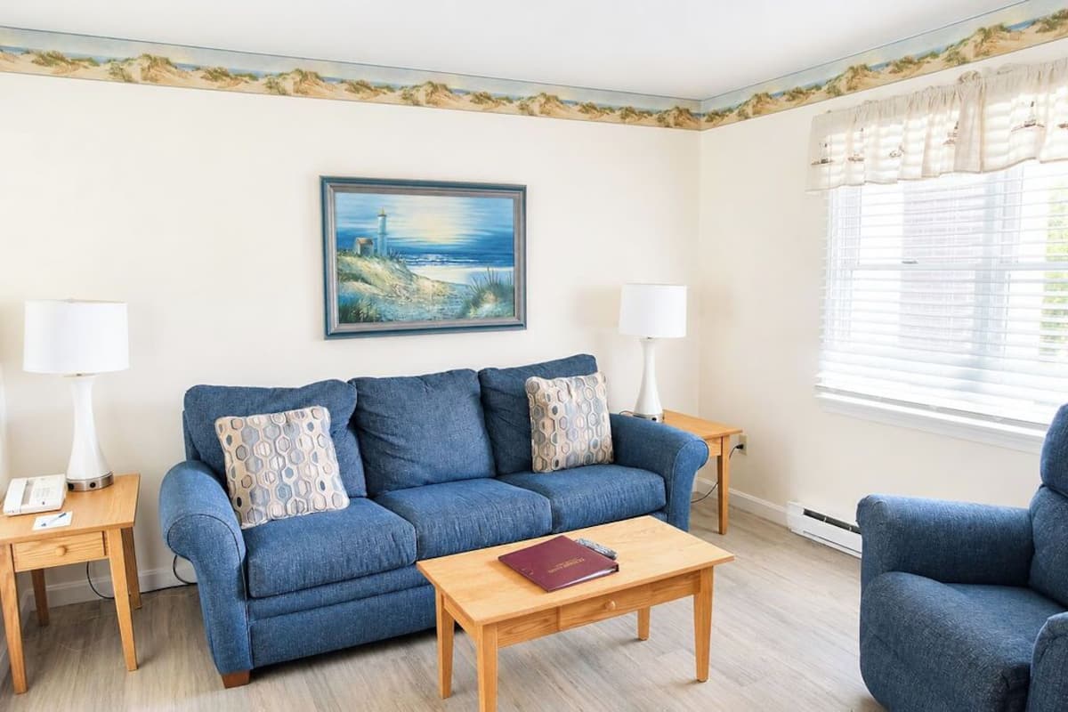 A living room with a blue sofa, two side tables, a wooden coffee table, and a painting on the wall.