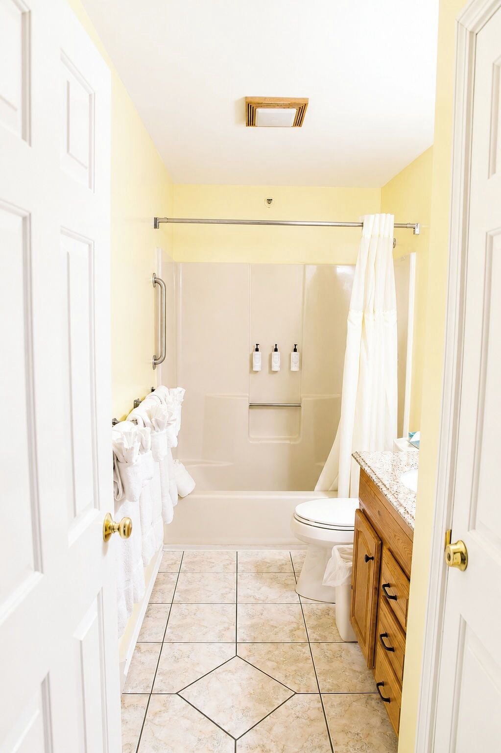A bathroom with a shower, toilet, and sink, featuring a tiled floor and white fixtures.