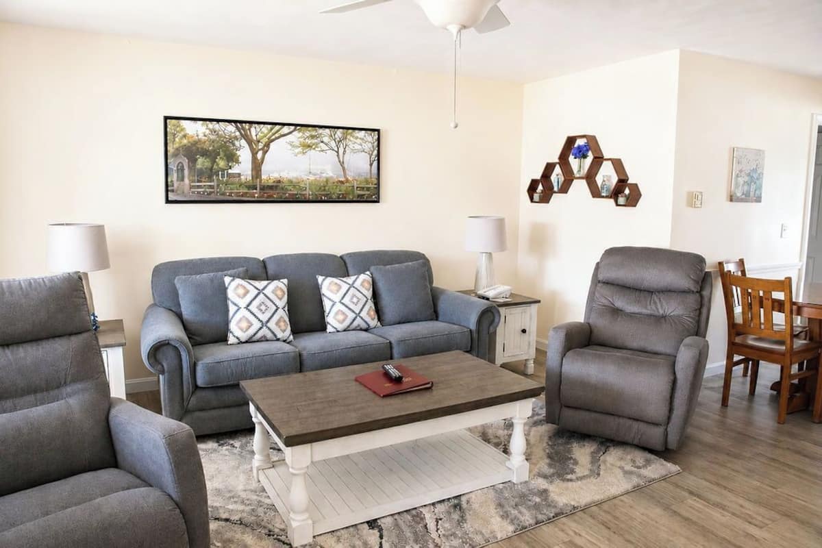 A living room with a grey sofa, a matching armchair, a coffee table, and a hexagonal wall decoration.