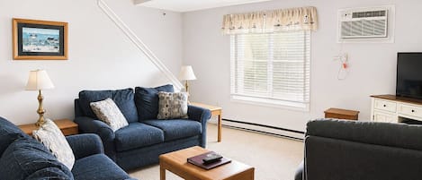 A living room with a sofa, armchair, coffee table, and a ceiling fan.
