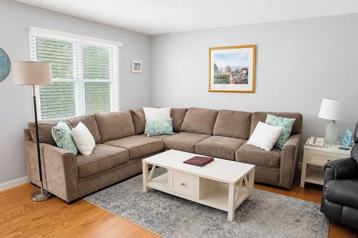A living room with a sectional sofa, a coffee table, a floor lamp, and a framed picture on the wall.