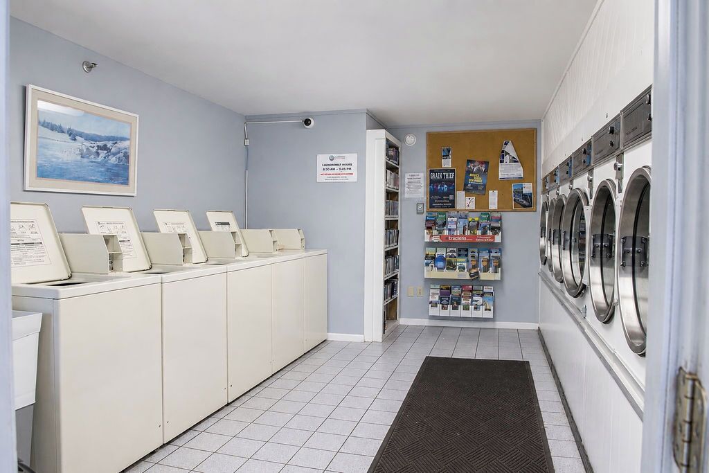 A laundry facility with multiple washing machines, a selection of detergents, and a framed picture on the wall.
