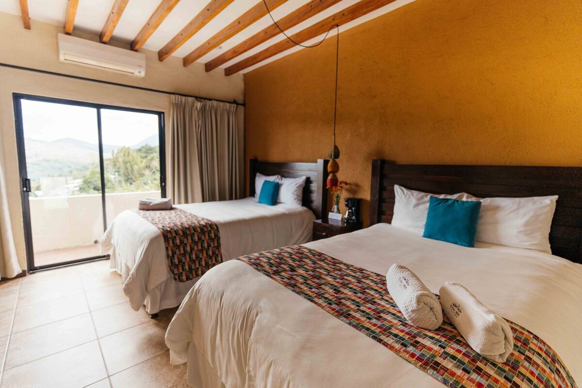 Ein Hotelzimmer mit zwei Betten, einer großen Schiebetür zum Balkon und Blick ins Freie.