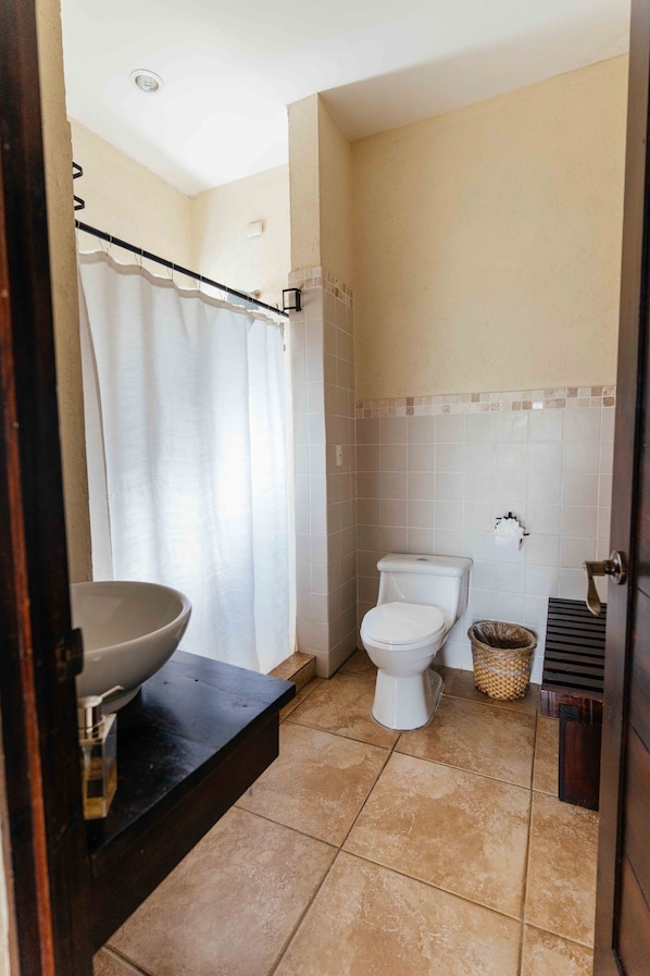 Een badkamer met toilet, wastafel en douchegordijn.
