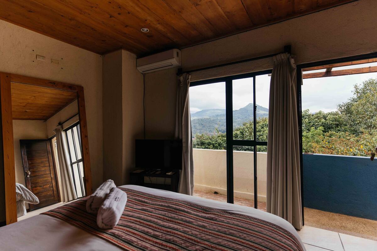 Ein Hotelzimmer mit Bett, Fernseher und einem Balkon mit Bergblick.