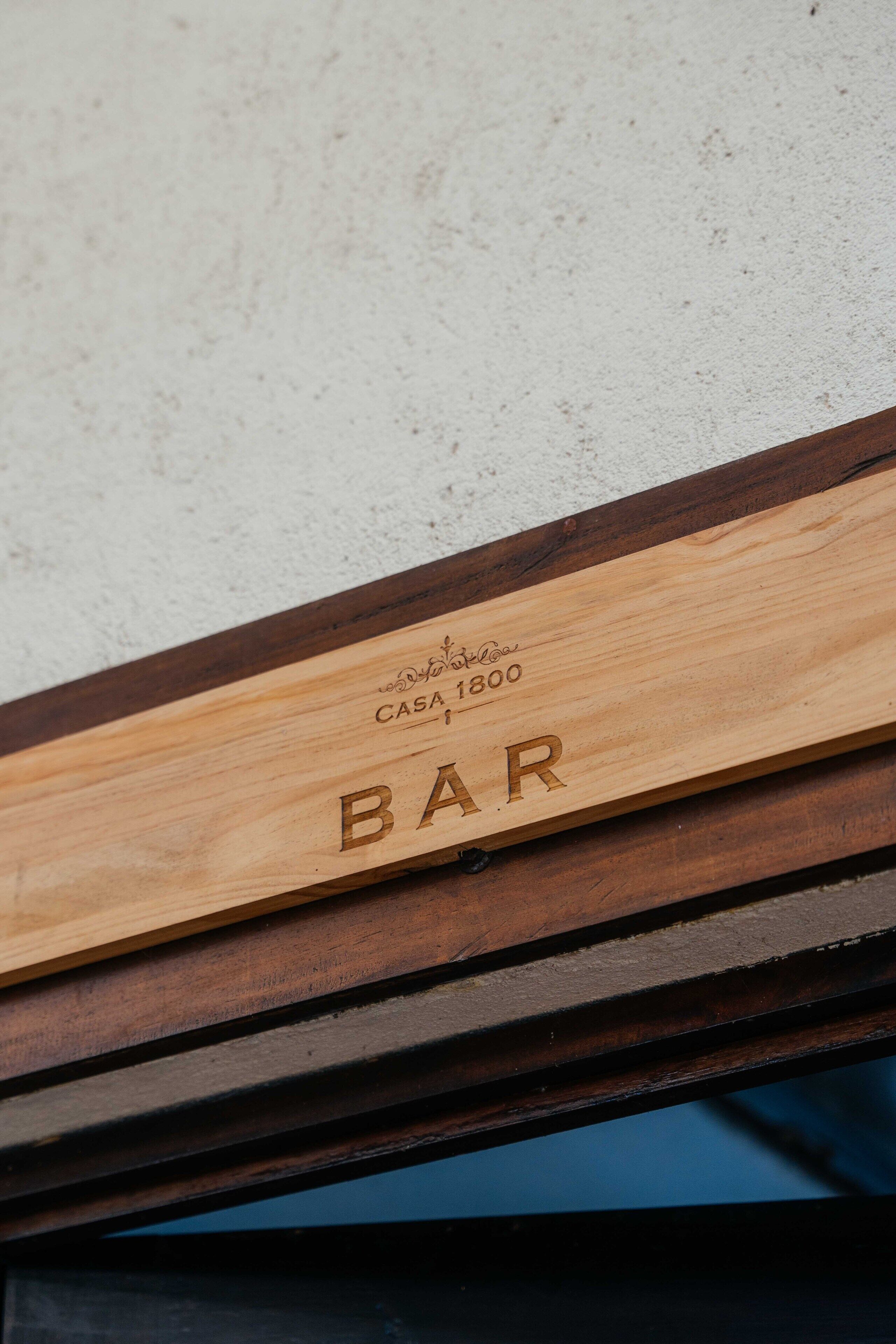 Balcão de madeira com a inscrição gravada "CASA 1800 BAR".