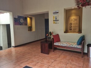 Ein Empfangsbereich mit einer Holzbank, einem kleinen Tisch und einem an der Wand befestigten Schild.