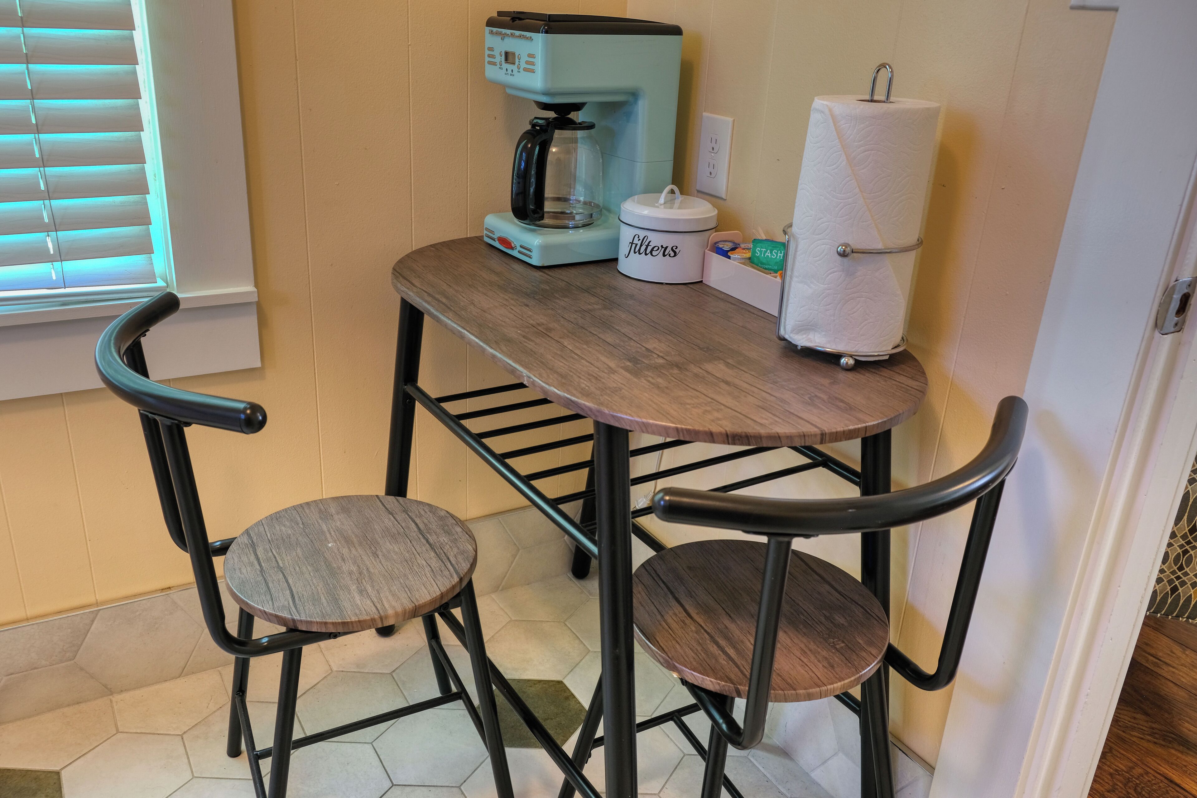 A small kitchen area with a coffee maker, a container labeled "filters," and a paper towel holder.