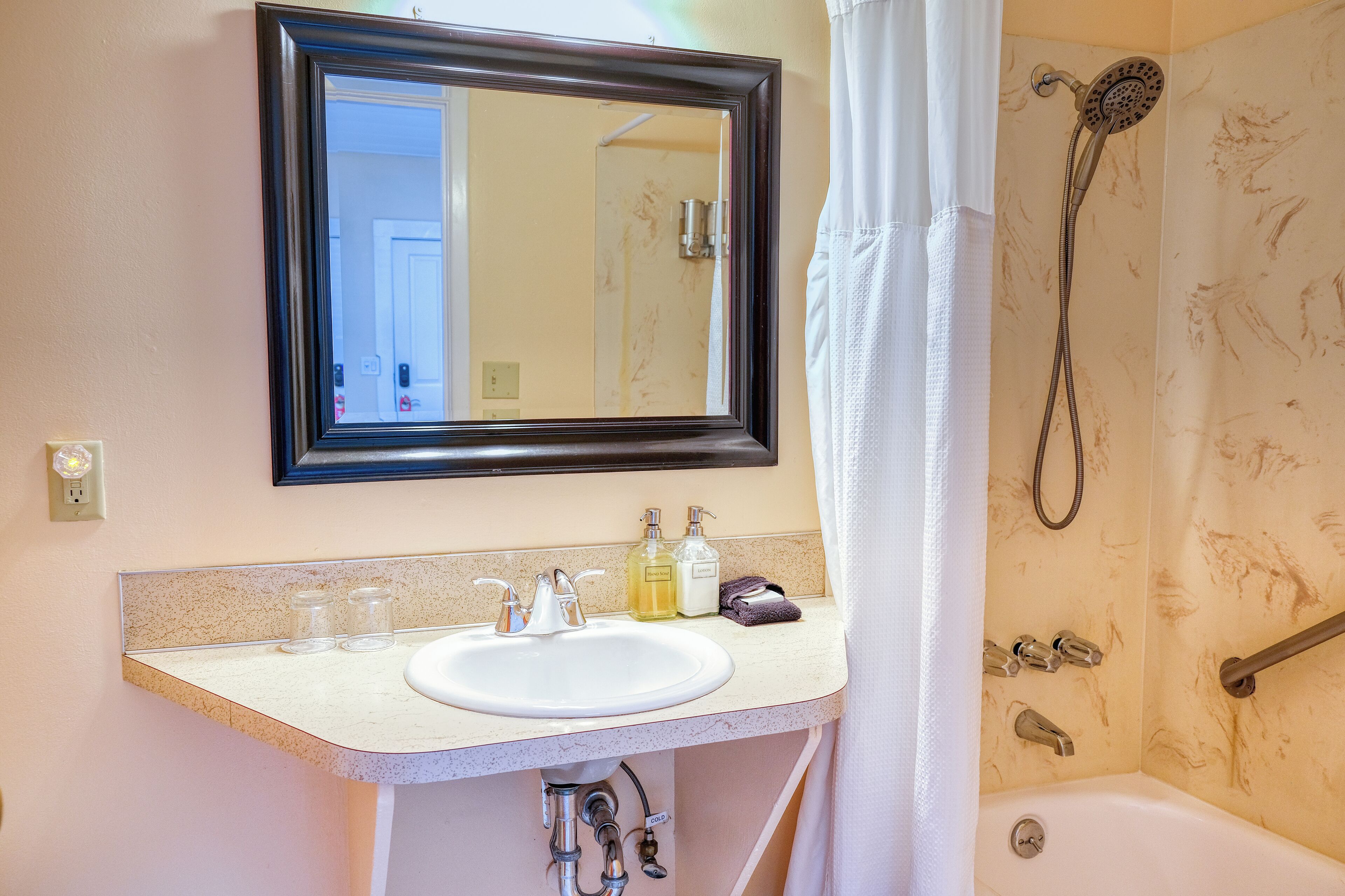 A bathroom with a white sink, mirror, and shower.
