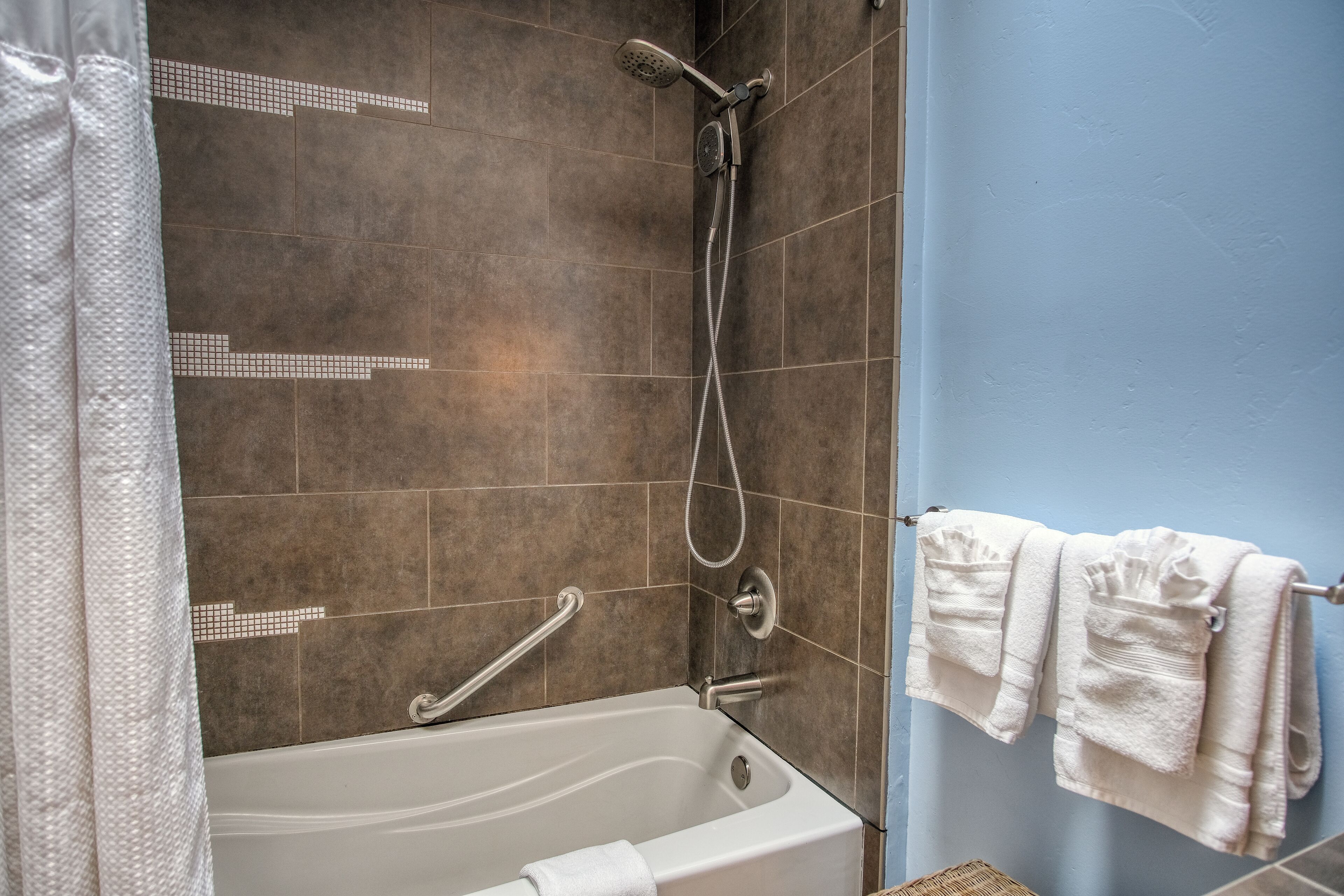 A bathroom with a bathtub, a shower, and a towel rack with towels.