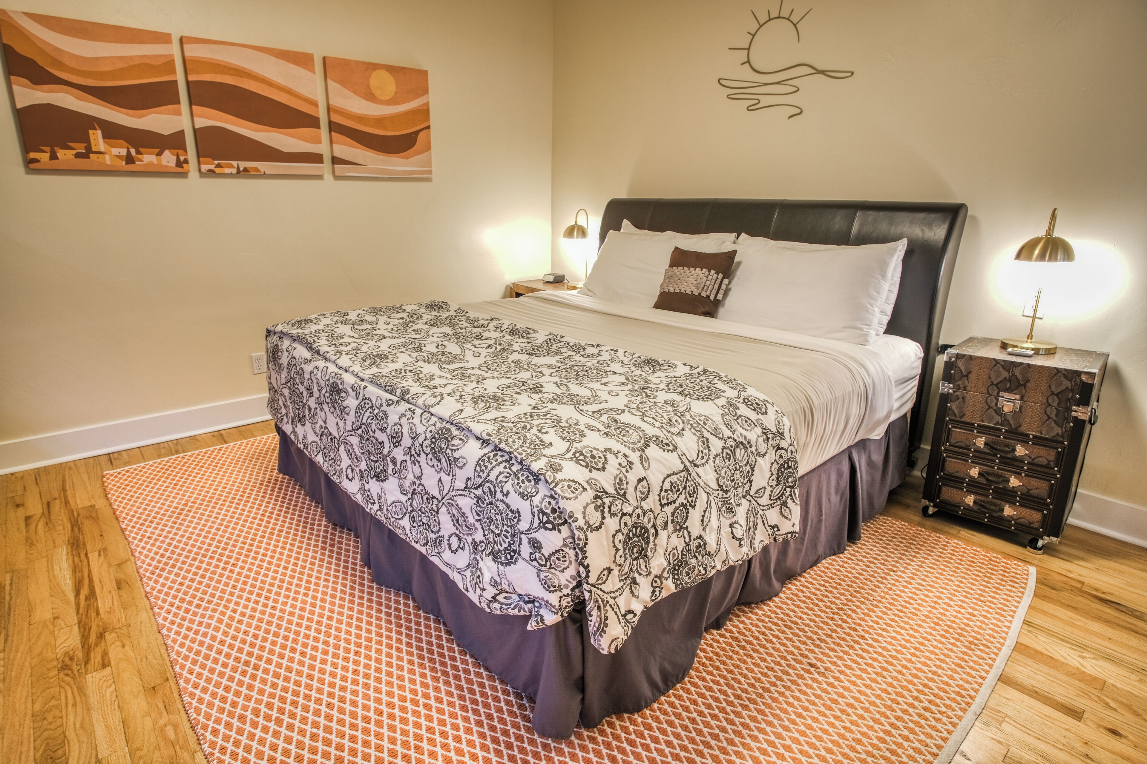 Un dormitorio ordenado con cama, mesita de noche y cómoda.