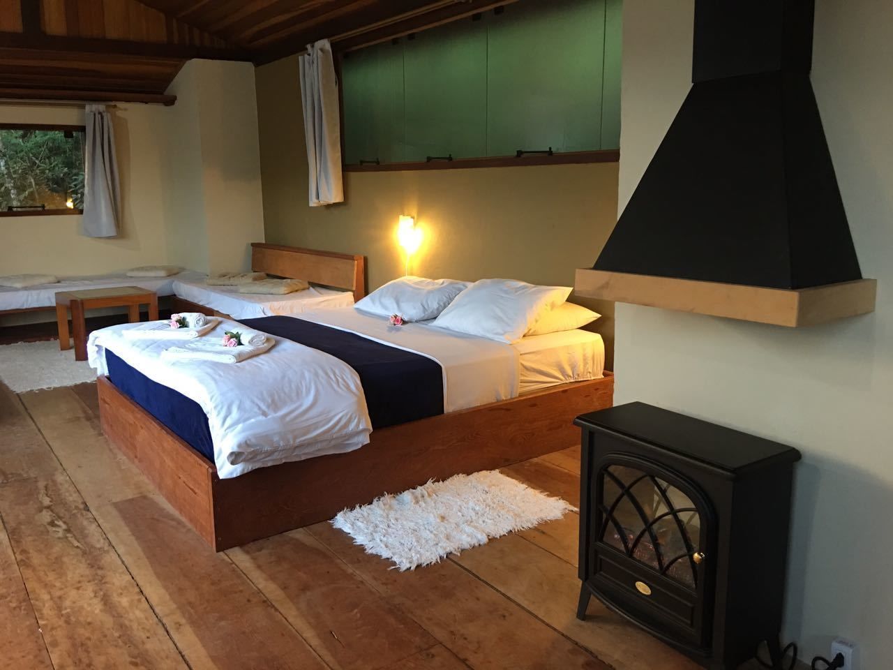 A room with two wooden beds, a white fluffy rug, and a black stove.