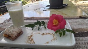 Ein Tablett mit einem Getränk, einem Gebäckstück und einer Blume auf einem Tisch.