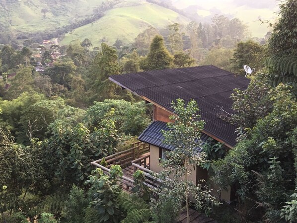 A traditional Japanese-style house with a tiled roof, surrounded by lush greenery and hills in the background. - Chales da Piscina Natural (Bocaina de Minas)