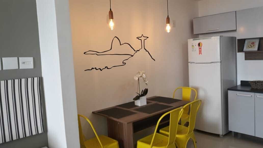 Una cocina moderna con una mesa de comedor y sillas, un refrigerador y una lámpara de pared.