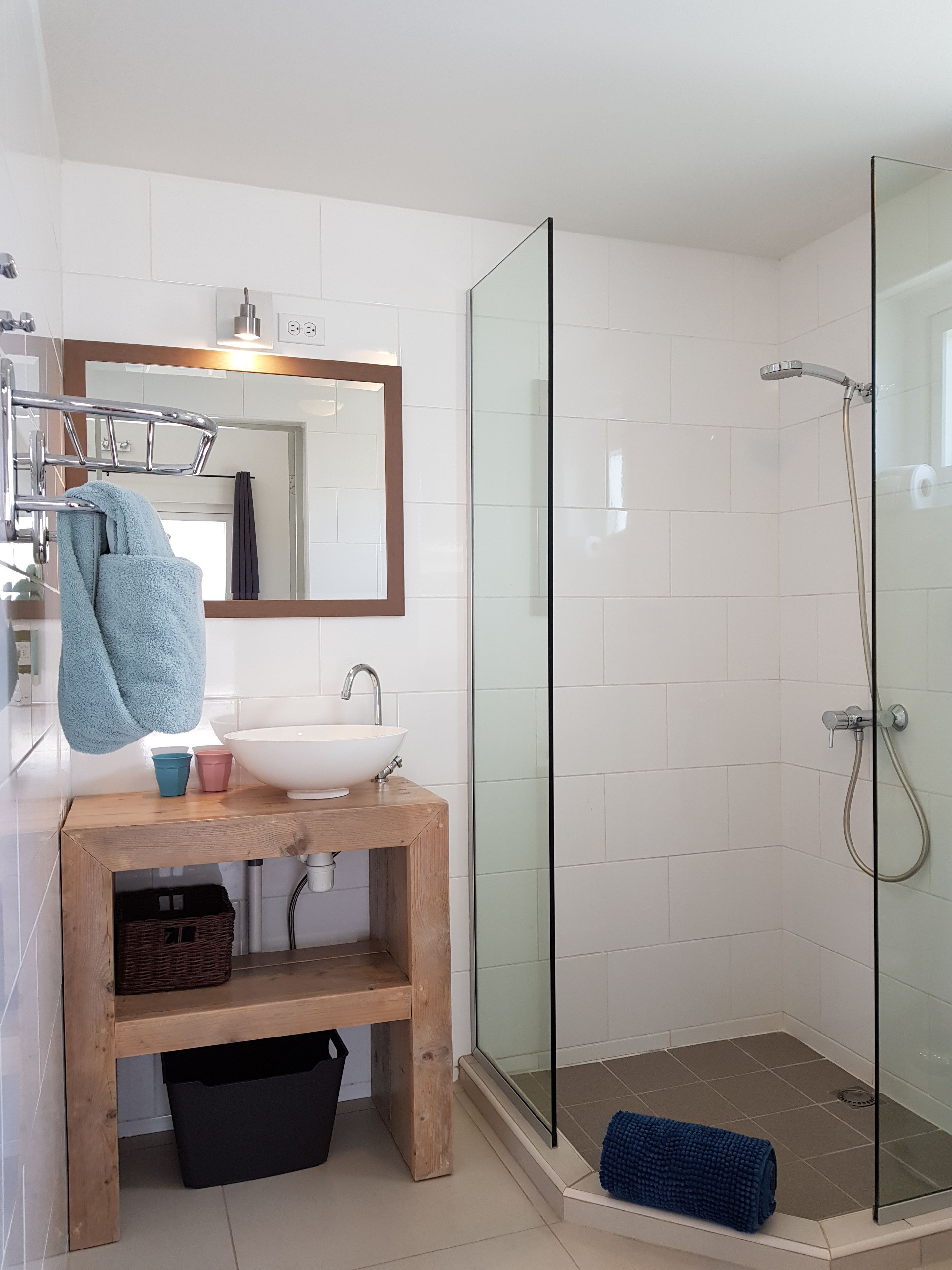 A bathroom with a wooden vanity, a white sink, a mirror, and a glass-enclosed shower.