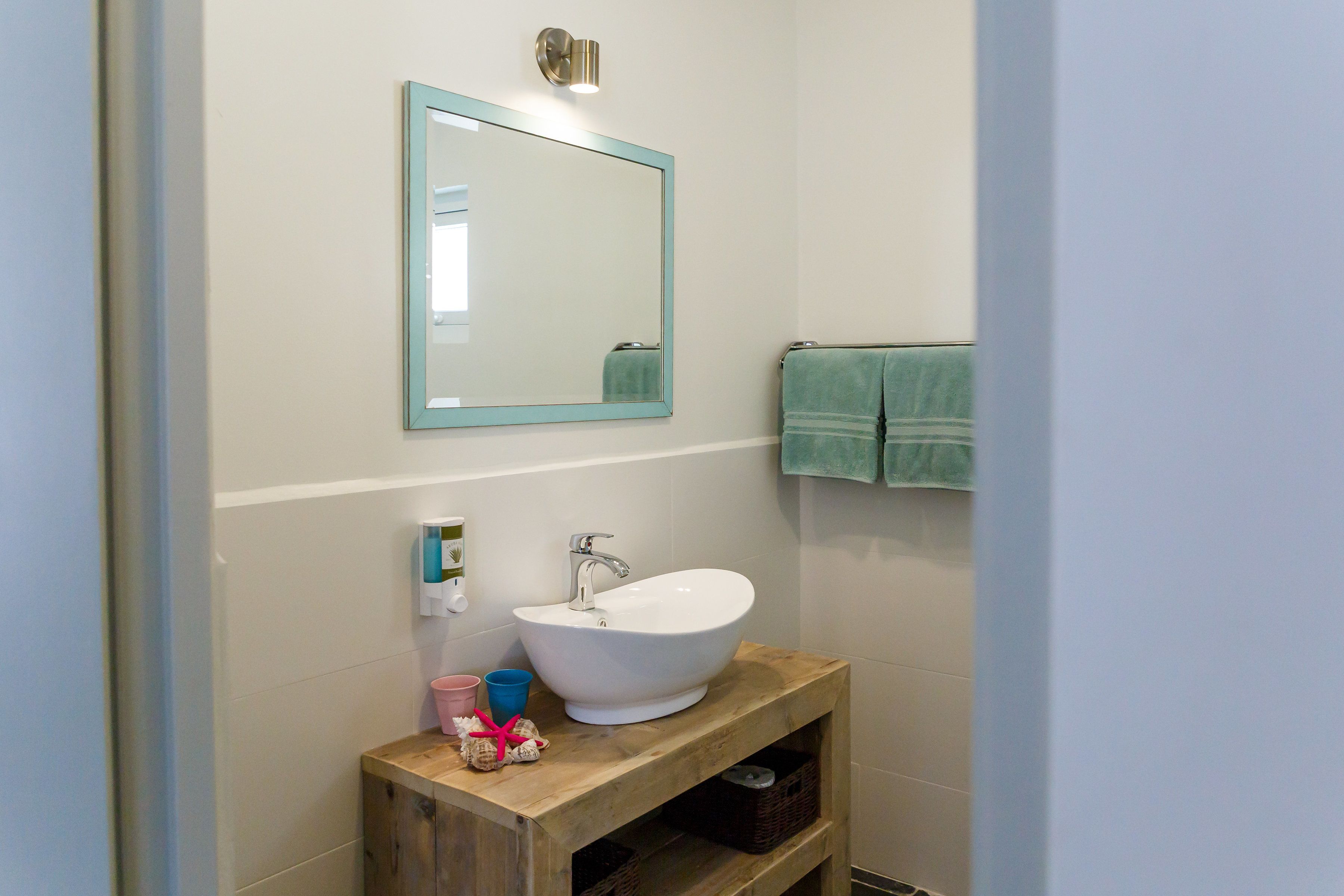A bathroom with a wooden vanity, a white sink, a mirror, and a towel rack.