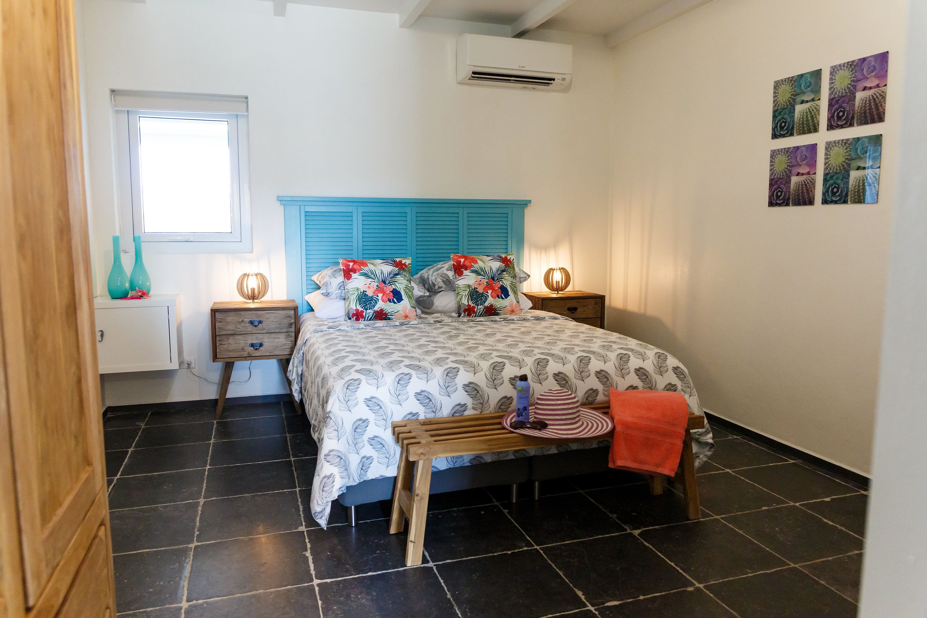 Een slaapkamer met een bed, twee nachtkastjes, een raam en een wandairconditioner.