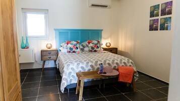 Een slaapkamer met een bed, twee nachtkastjes, een raam en een wandairconditioner.