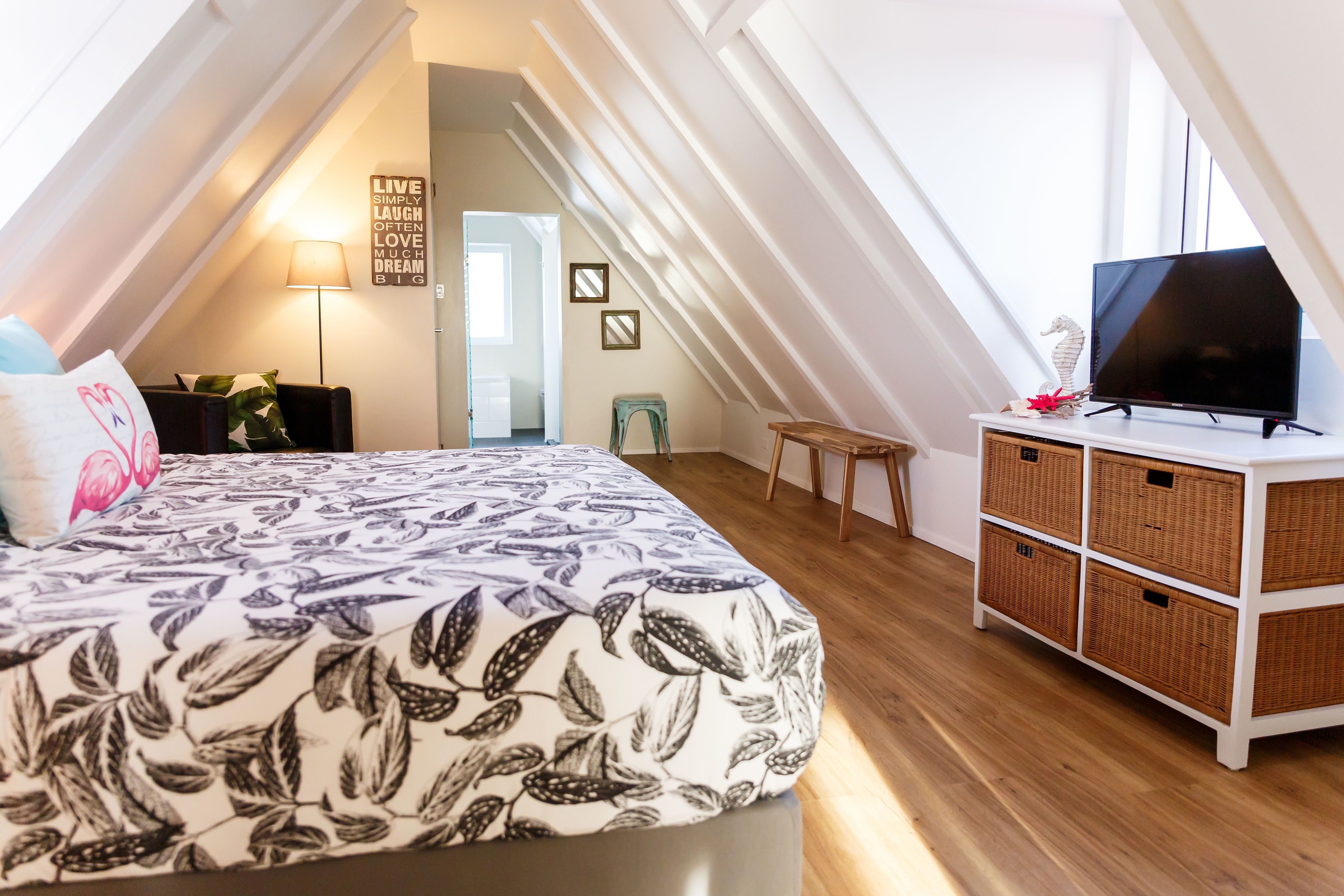 Una habitación con cama, televisión, cómoda y tragaluz.