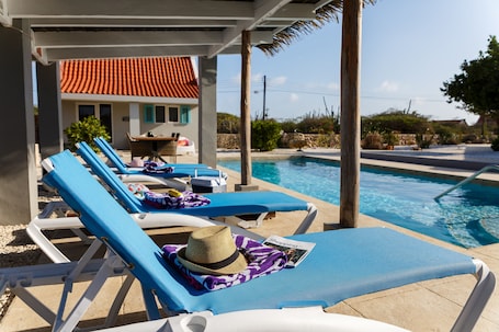 Una piscina al aire libre, sombrillas, sillones reclinables de piscina