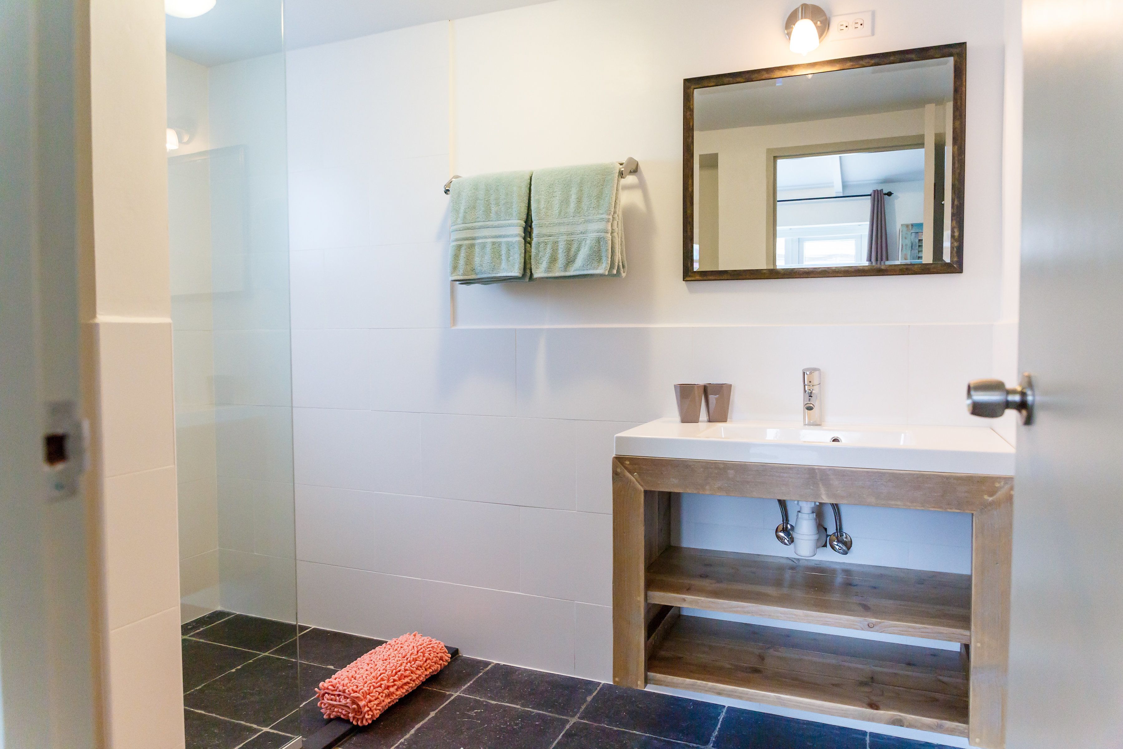 Ein Badezimmer mit einem weißen Waschbecken, einem Spiegel und einem Handtuchhalter.