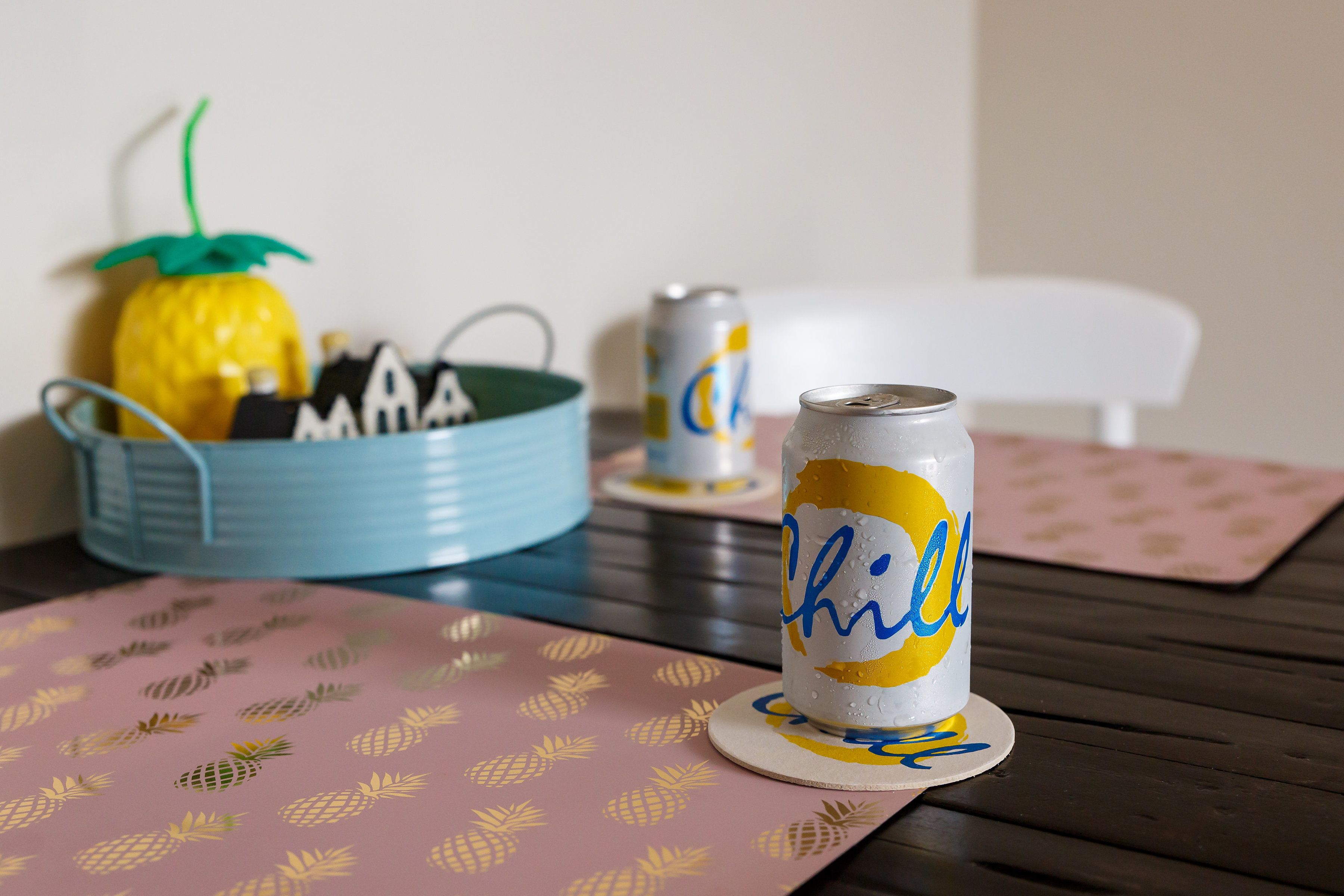 Een tafel met een ananas, een blikje bier en een blauwe kom.