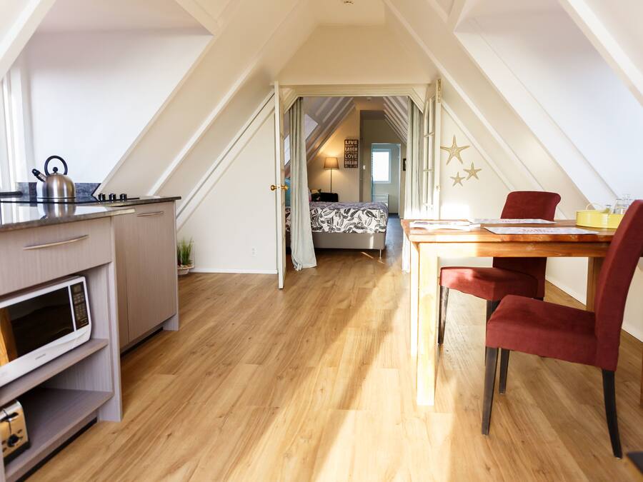 Un dormitorio estilo loft moderno con una cama grande, un escritorio y un comedor.