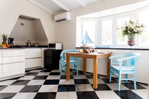 Una cocina con piso a cuadros, una mesa de madera y dos sillas azules.