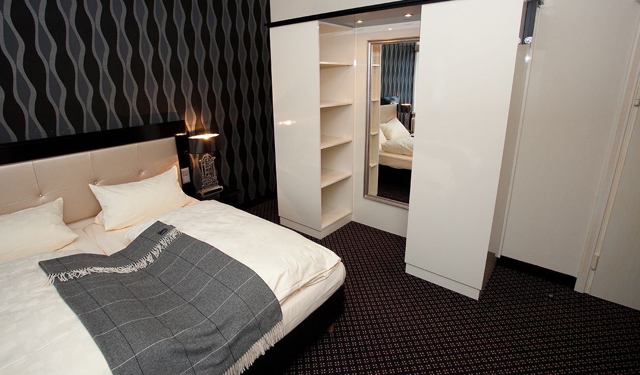 Un dormitorio con cama, armario y espejo.