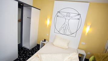 A hotel room with a bed, a wall-mounted artwork of a human figure, bedside tables, and a door leading to a hallway.