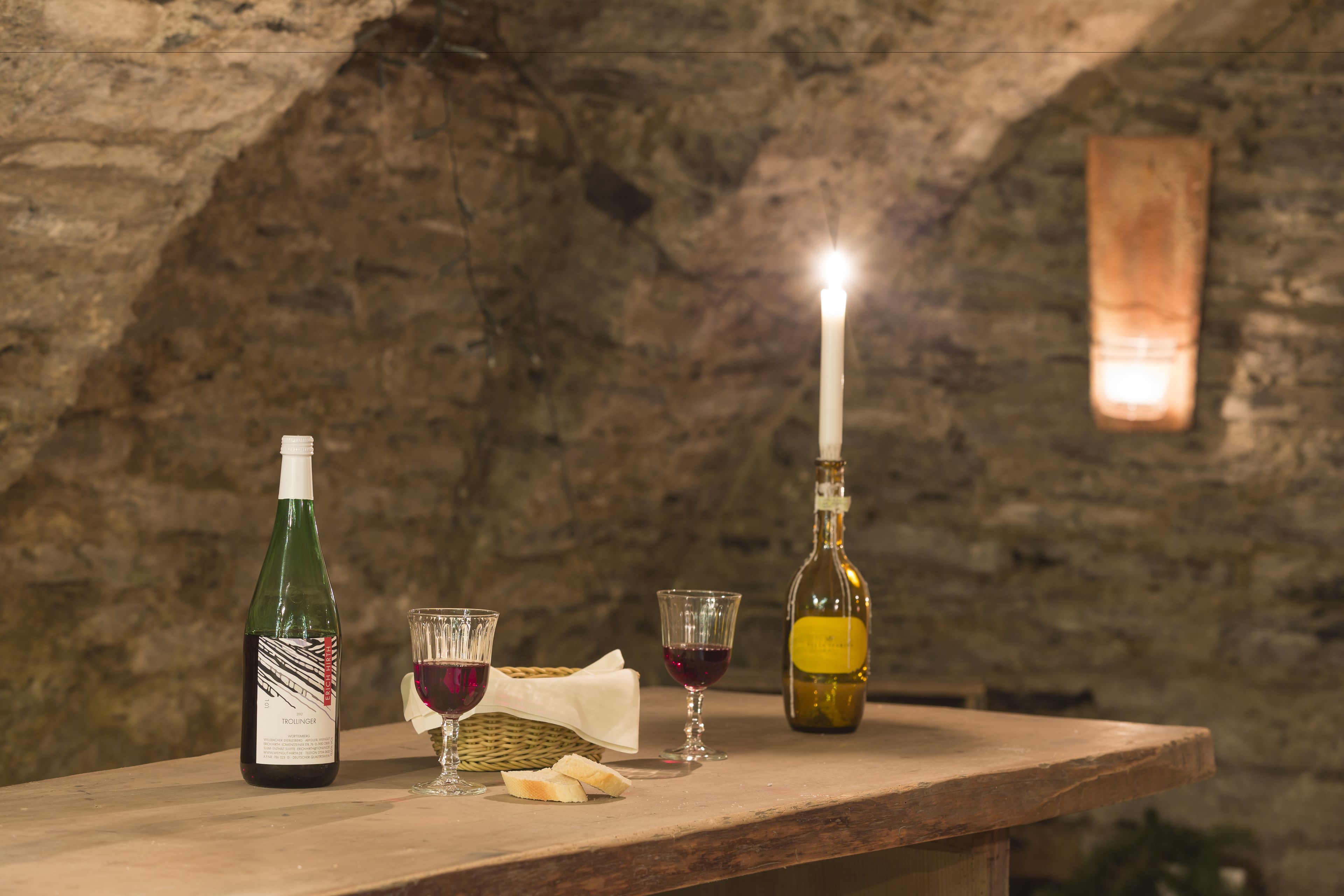 Una mesa de madera con una botella de vino, dos copas y una vela.