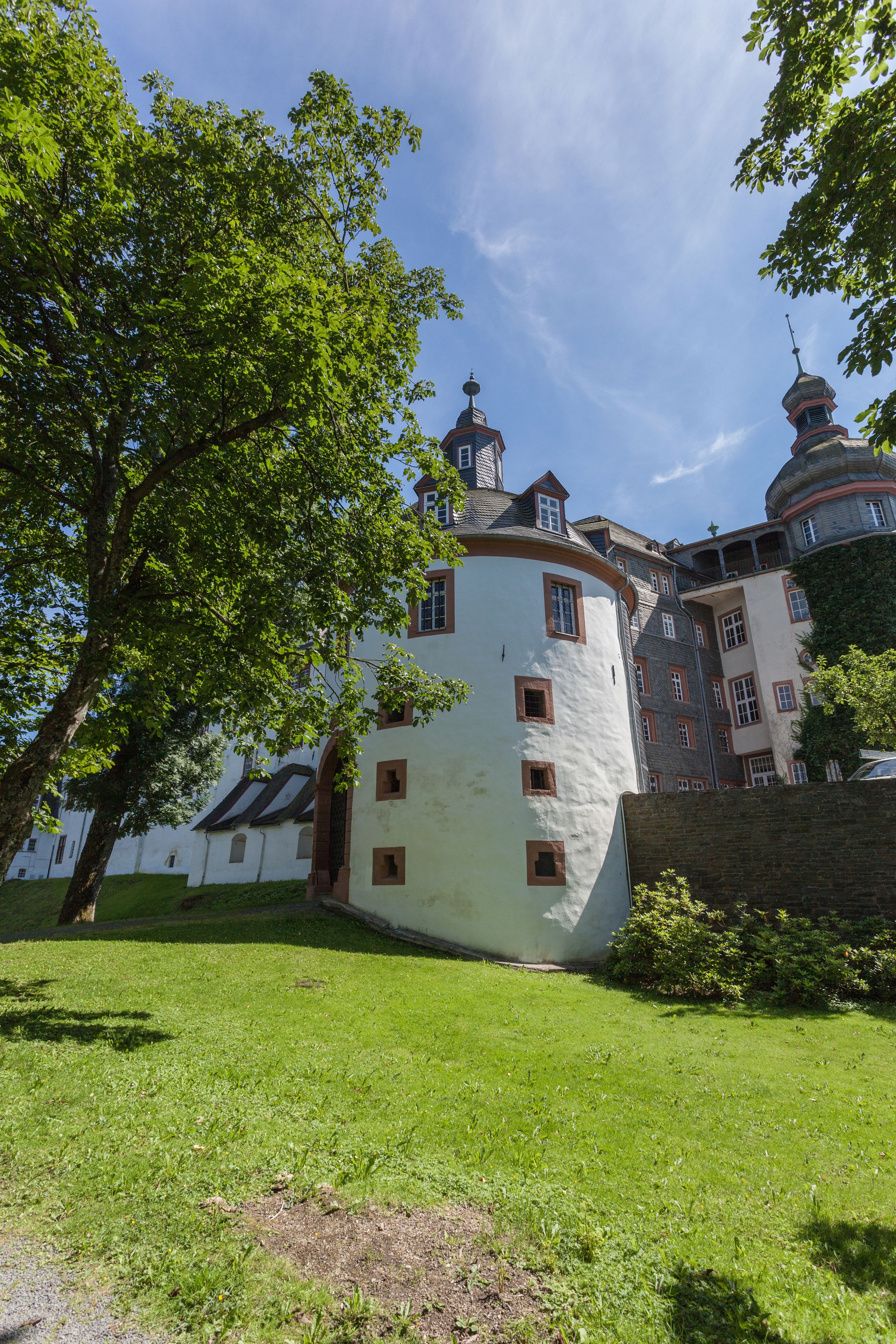 A historic building with a round tower, surrounded by lush greenery.