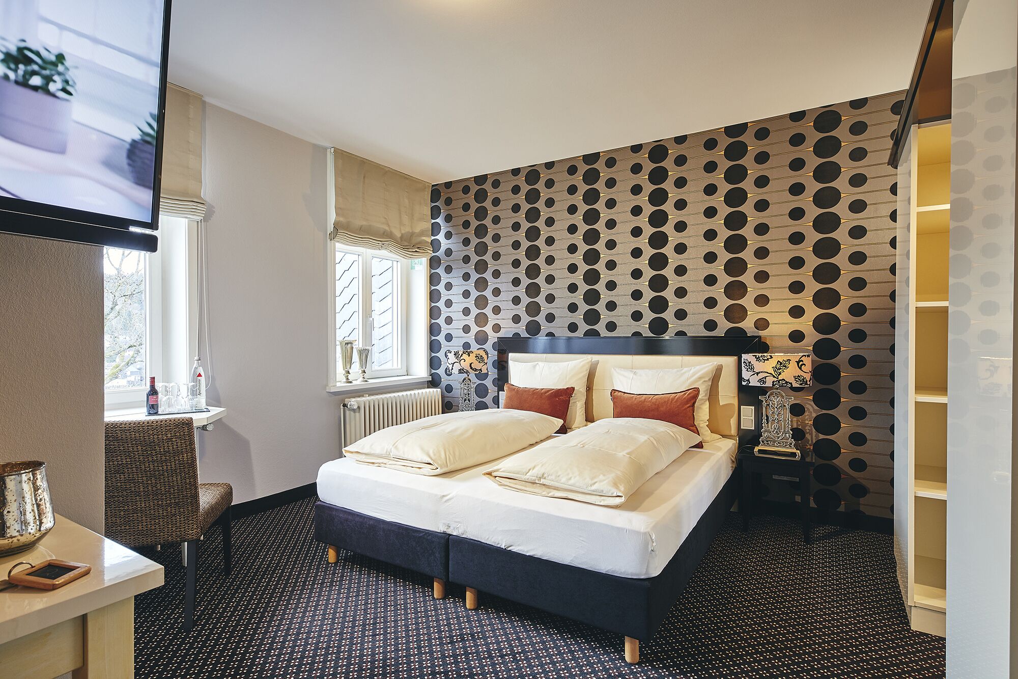 A bedroom with a bed, a window, a radiator, and a patterned wall.