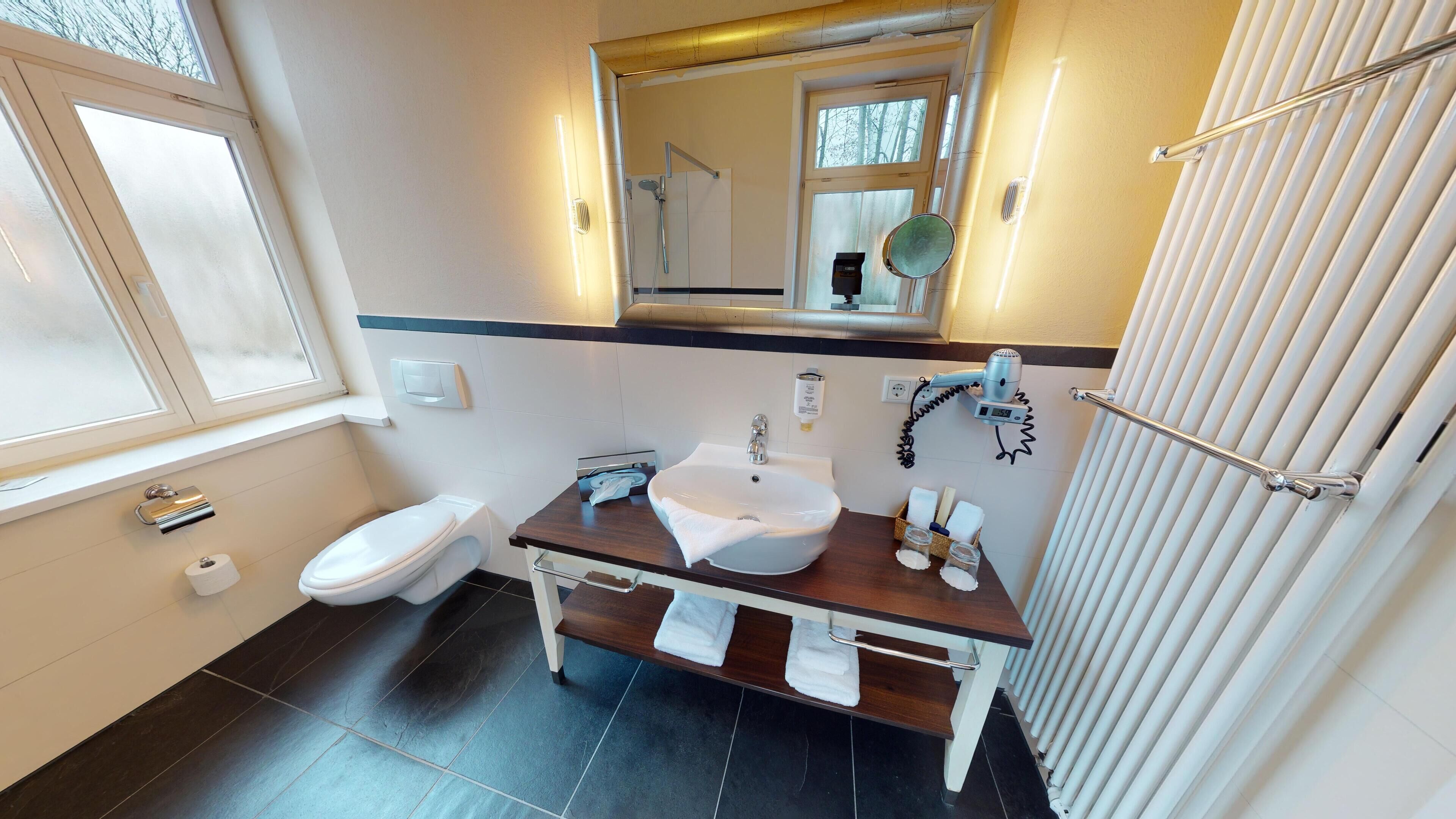 A bathroom with a toilet, sink, and shower.