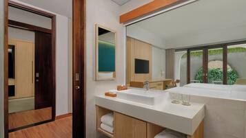 Un baño moderno con un espejo grande, dos lavamanos, armarios de madera y vistas a zonas verdes.