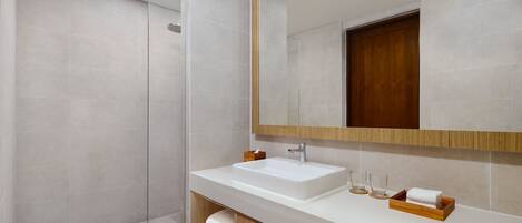 A modern bathroom with a large mirror, a white sink, and a shower area.
