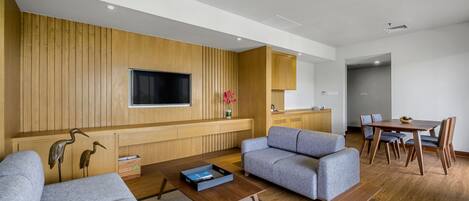 A modern living room with a sofa, a coffee table, and a TV mounted on the wall.