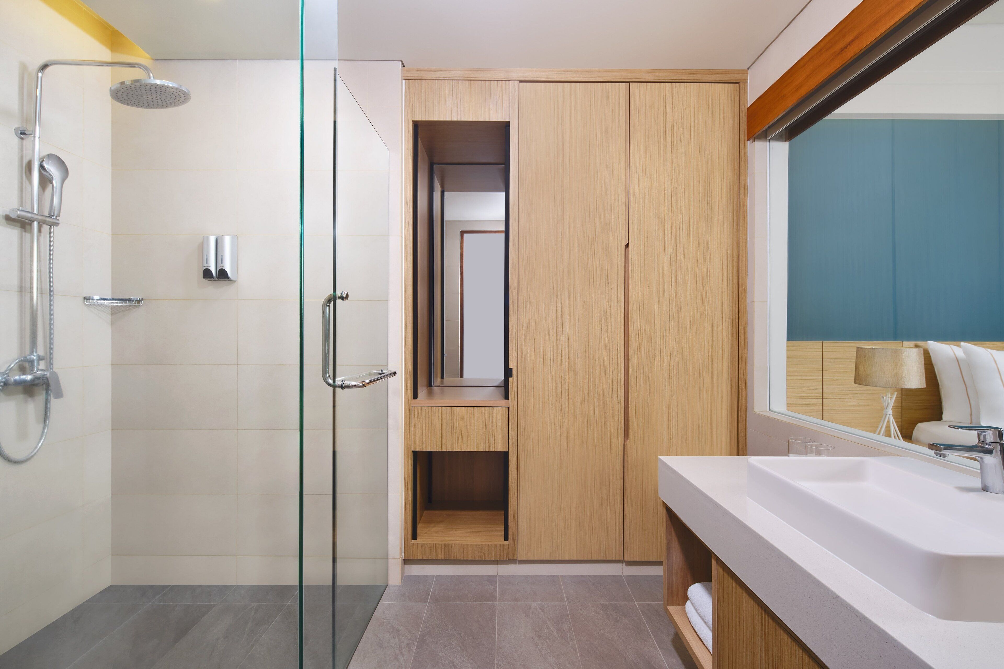 Une salle de bain moderne avec une douche à l’italienne en verre, un meuble-lavabo en bois avec un miroir et un grand lavabo.