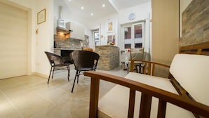 A modern kitchen with a stone island, two wicker chairs, and a wooden bench. - Vebis Guesthouse (Rome)
