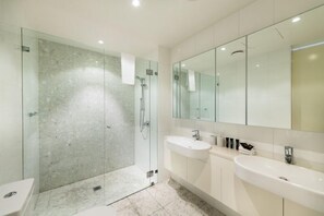 A modern bathroom with a glass-enclosed shower, two sinks, and a large mirror.