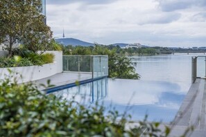 Piscina infinita con vistas despejadas a un río y montañas lejanas.